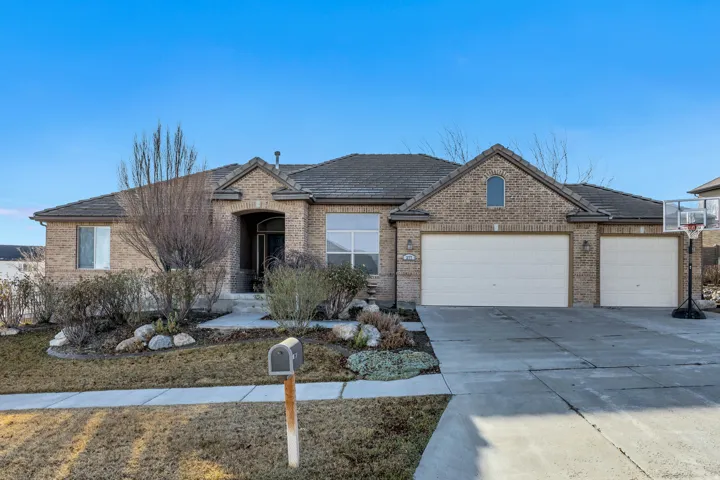 View of front of home featuring brick siding, an attached garage, concrete driveway, and a tile roof