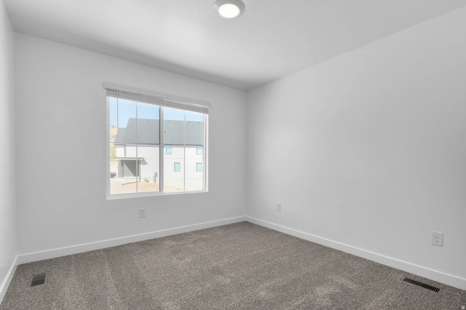 Spare room featuring baseboards and dark carpet
