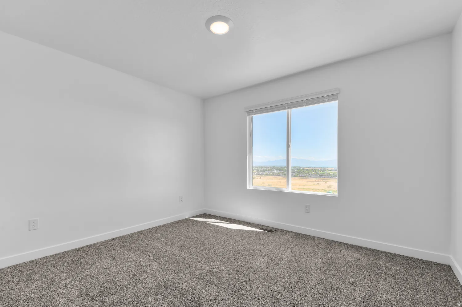 Spare room featuring baseboards and dark carpet