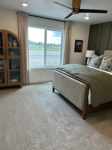 Spacious room featuring light gray carpet flooring, recessed lighting, and a contemporary ceiling fan with a brass-finish fixture