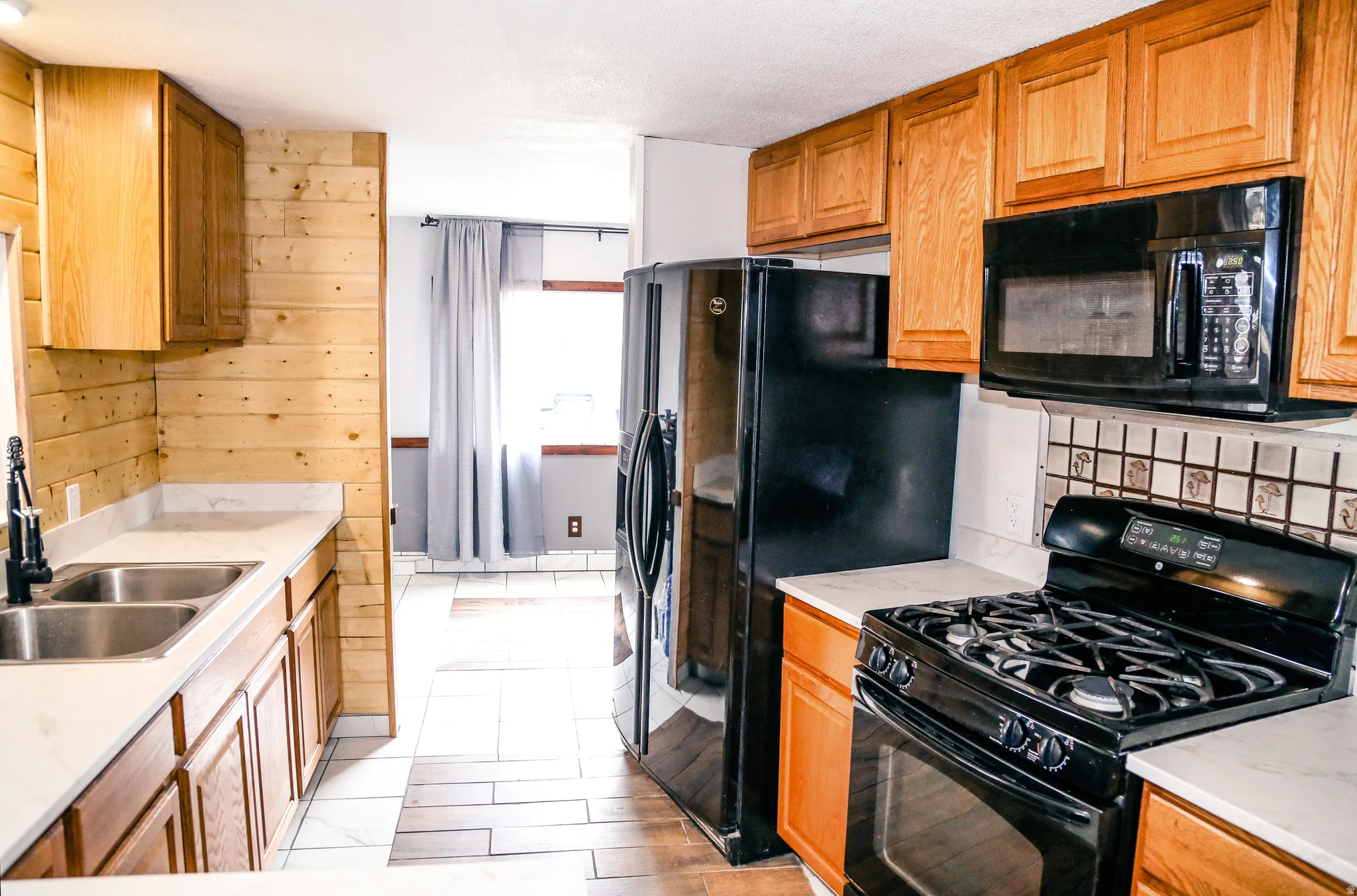 Kitchen featuring black appliances, light countertops, and wood finish cabinetry