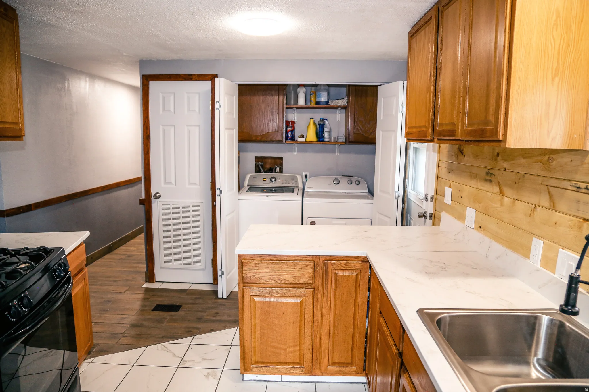 Kitchen featuring wood finish cabinets, gas stove, light countertops, independent washer and dryer, and a textured ceiling