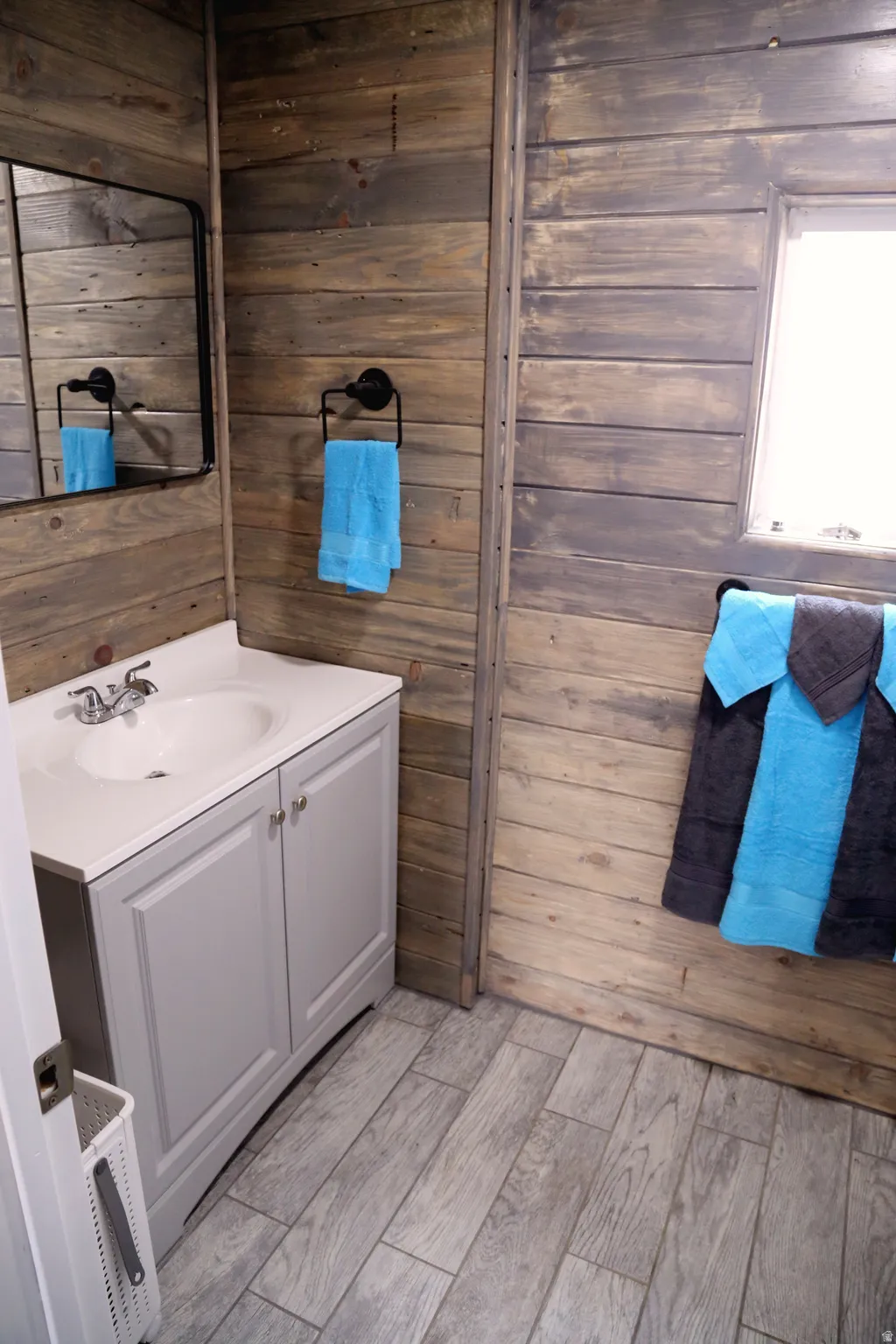 Bathroom featuring wooden walls, vanity, and wood tiled floors