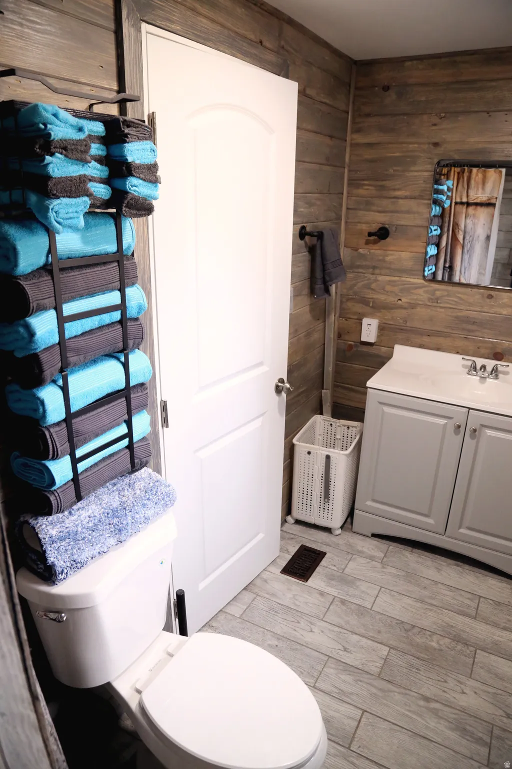 Bathroom with wooden walls, vanity, and light wood finished floors