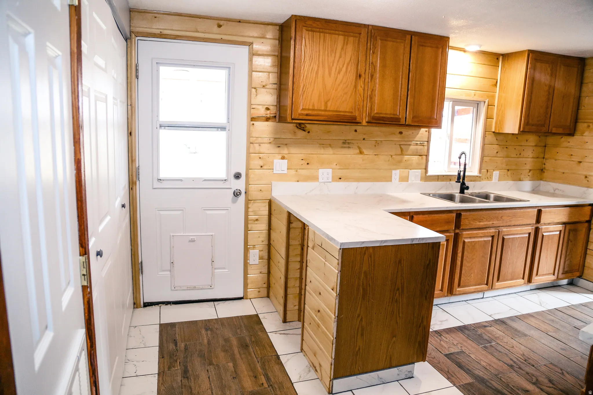 Kitchen with wood finish cabinets, light countertops, wood walls, and a peninsula