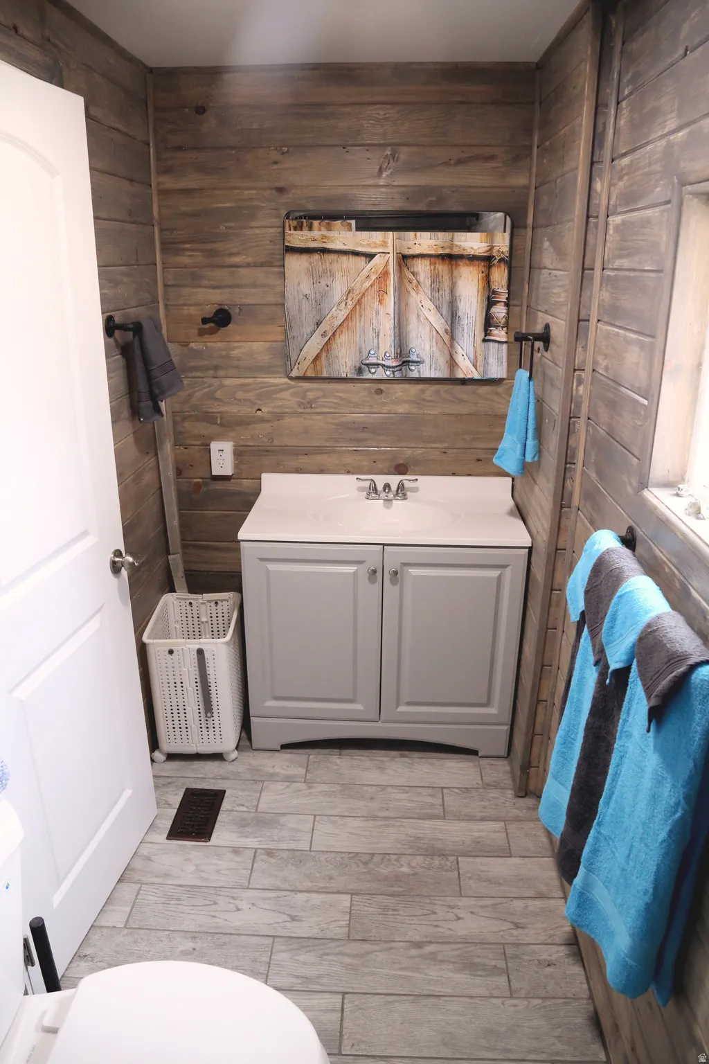 Bathroom featuring vanity, wooden walls, and wood finish floors