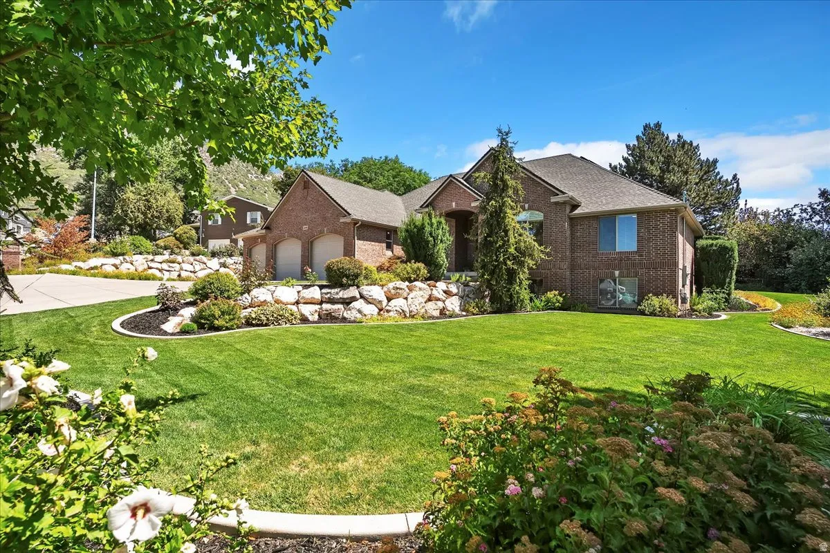 View of front facade featuring brick siding, a front yard, and an attached garage