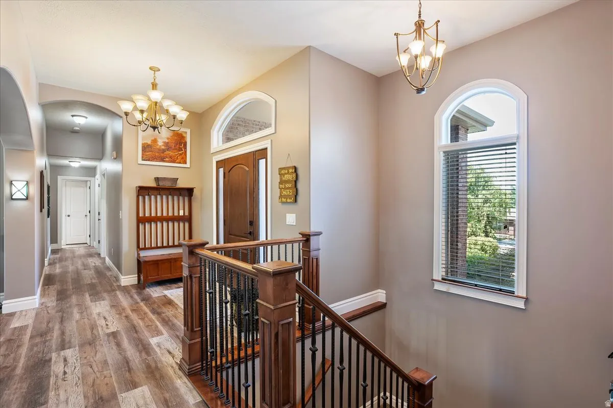 Entrance foyer with hanging lights, wood finished floors, and arched walkways