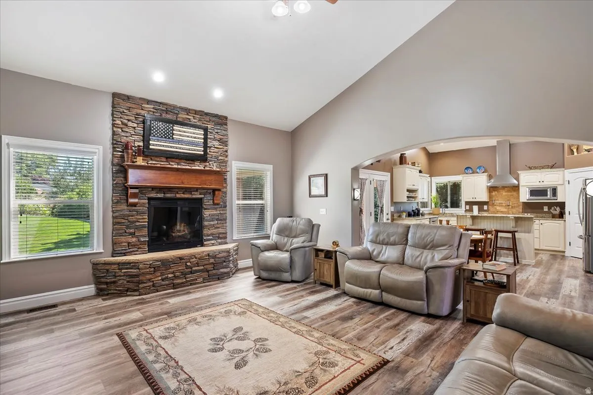 Living room featuring plenty of natural light, wood finished floors, arched walkways, ceiling fan, and vaulted ceiling