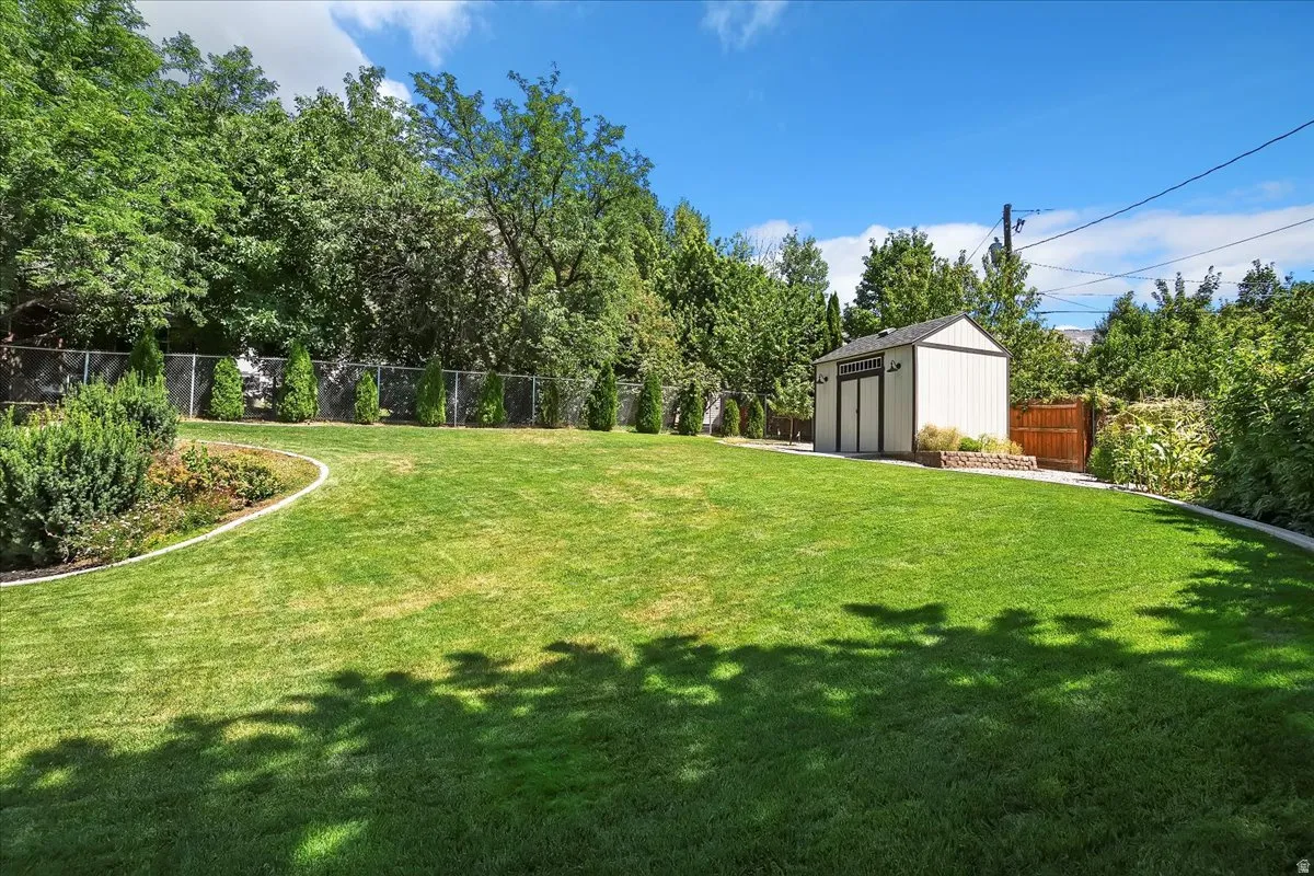 Fenced backyard featuring a storage unit