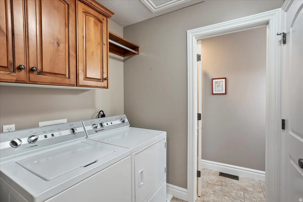 Laundry area with cabinet space, washer and clothes dryer, and a textured ceiling