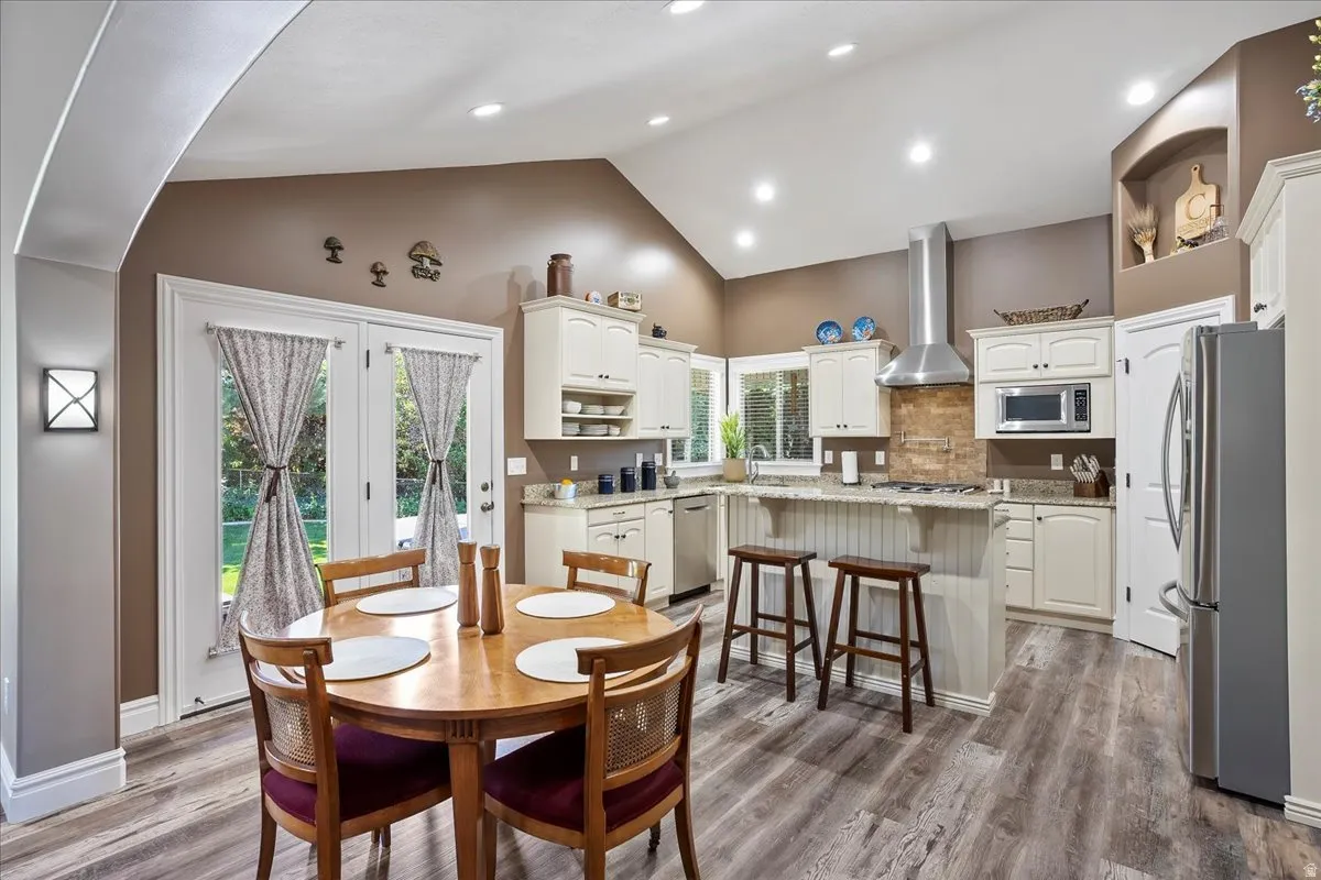 Dining area with a high ceiling, dark wood-type flooring, and recessed lighting