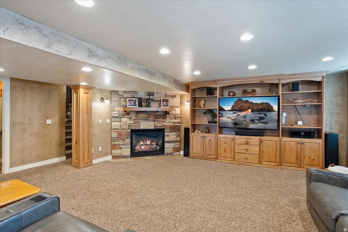Carpeted living room with recessed lighting and a stone fireplace