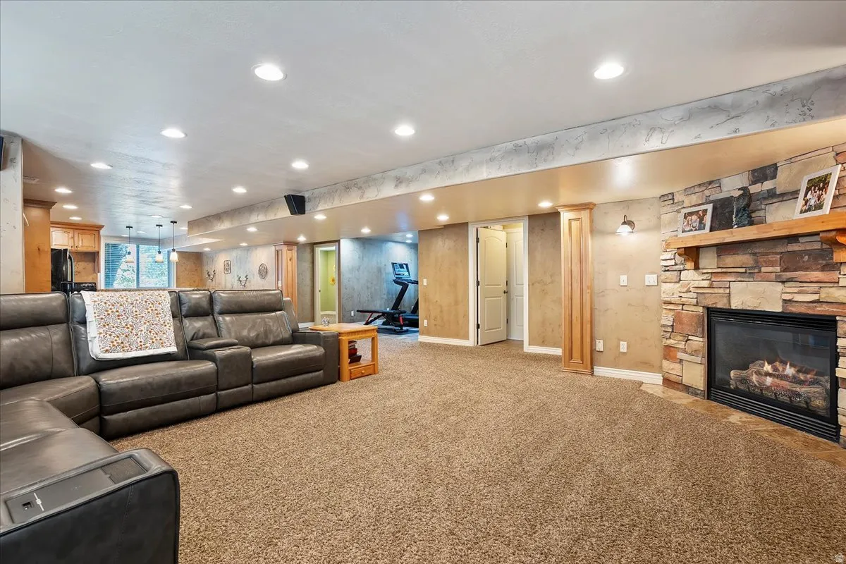 Living area featuring carpet floors, recessed lighting, and a stone fireplace