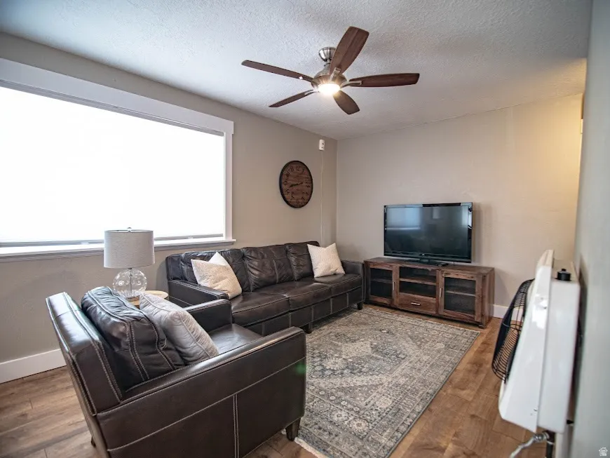 Living area featuring wood finished floors, a textured ceiling, and a ceiling fan