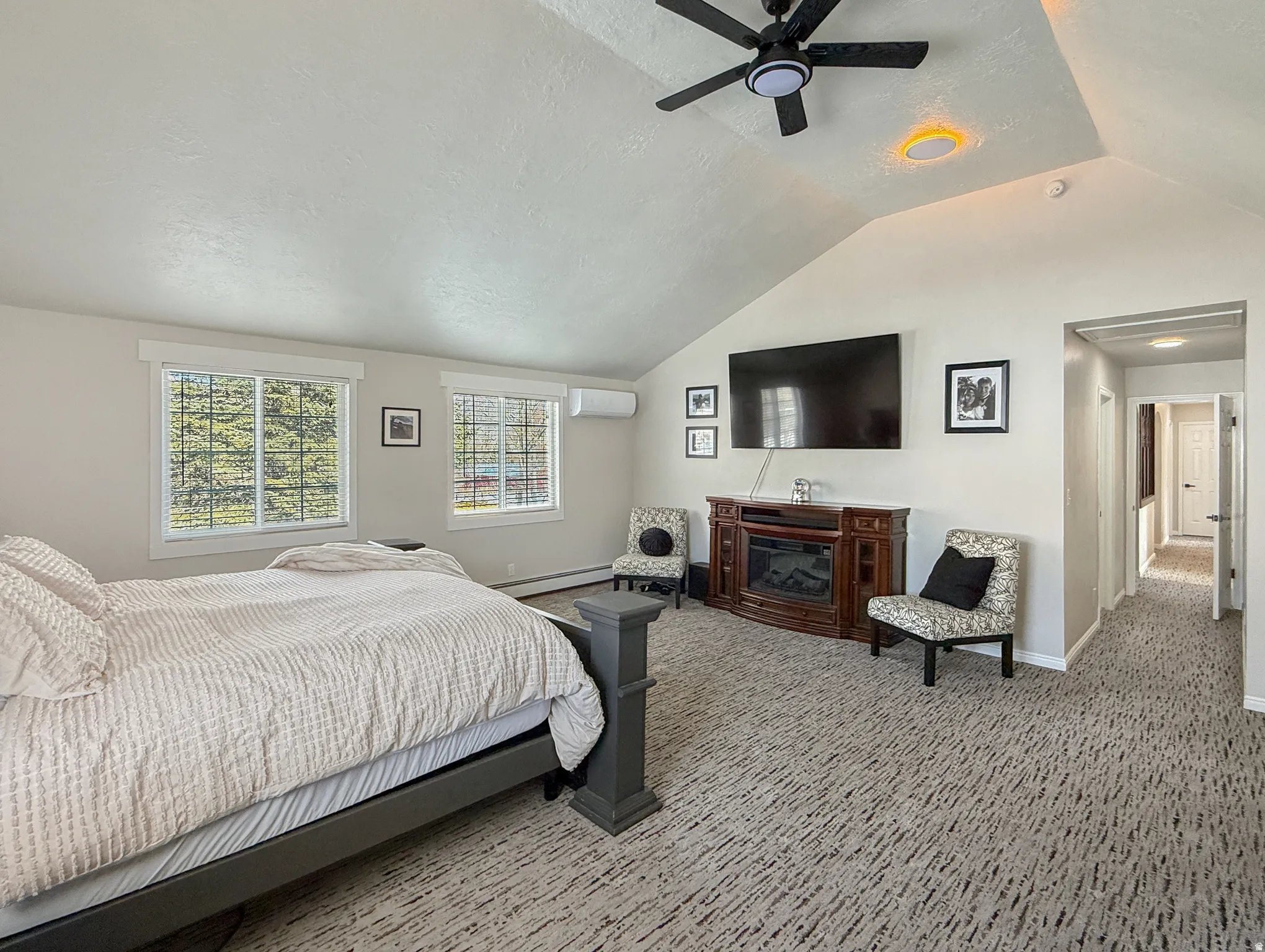 Bedroom featuring a textured ceiling, a baseboard heating unit, ceiling fan, and carpet flooring