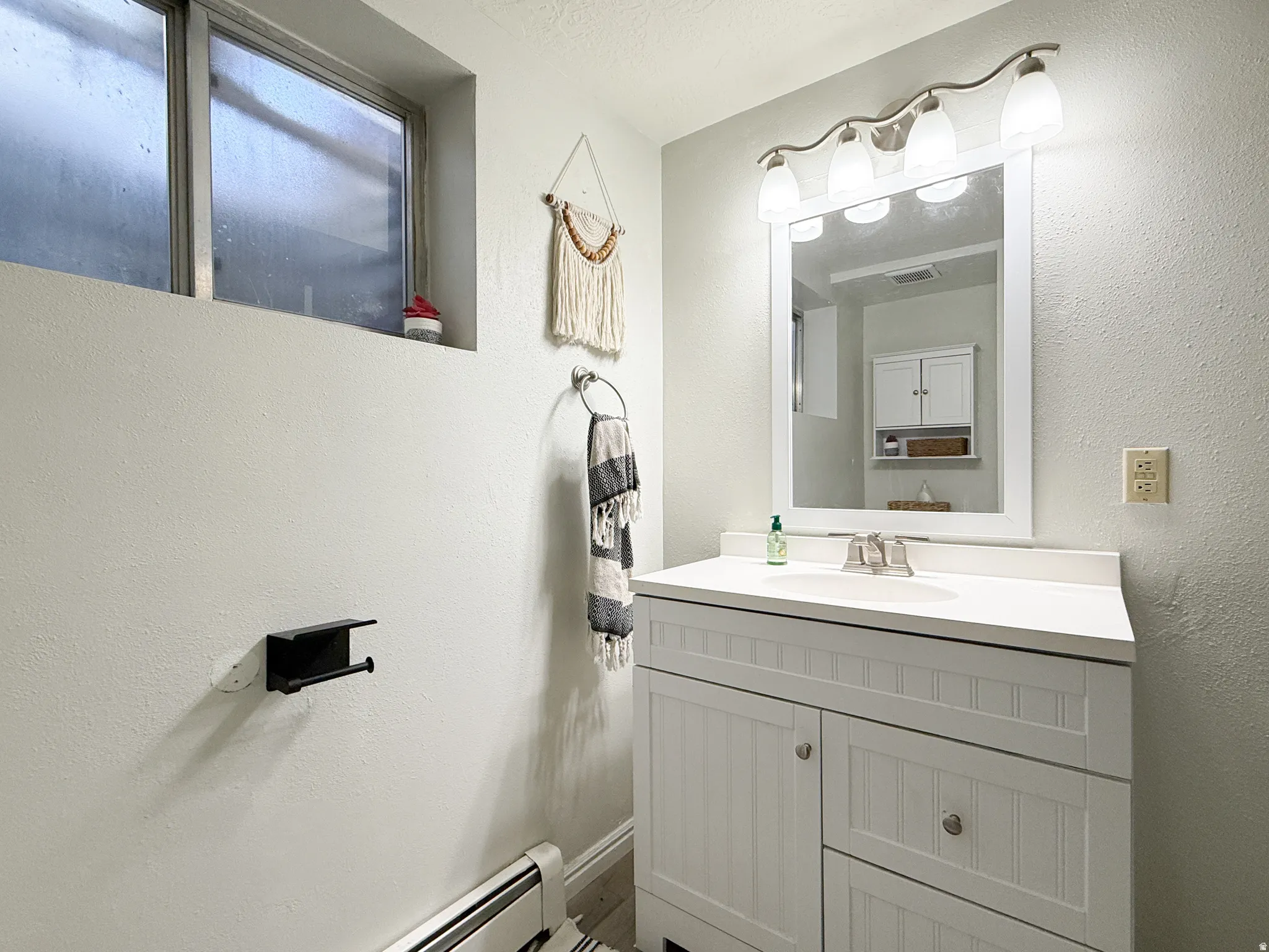 Bathroom with vanity, a baseboard radiator, and a textured wall