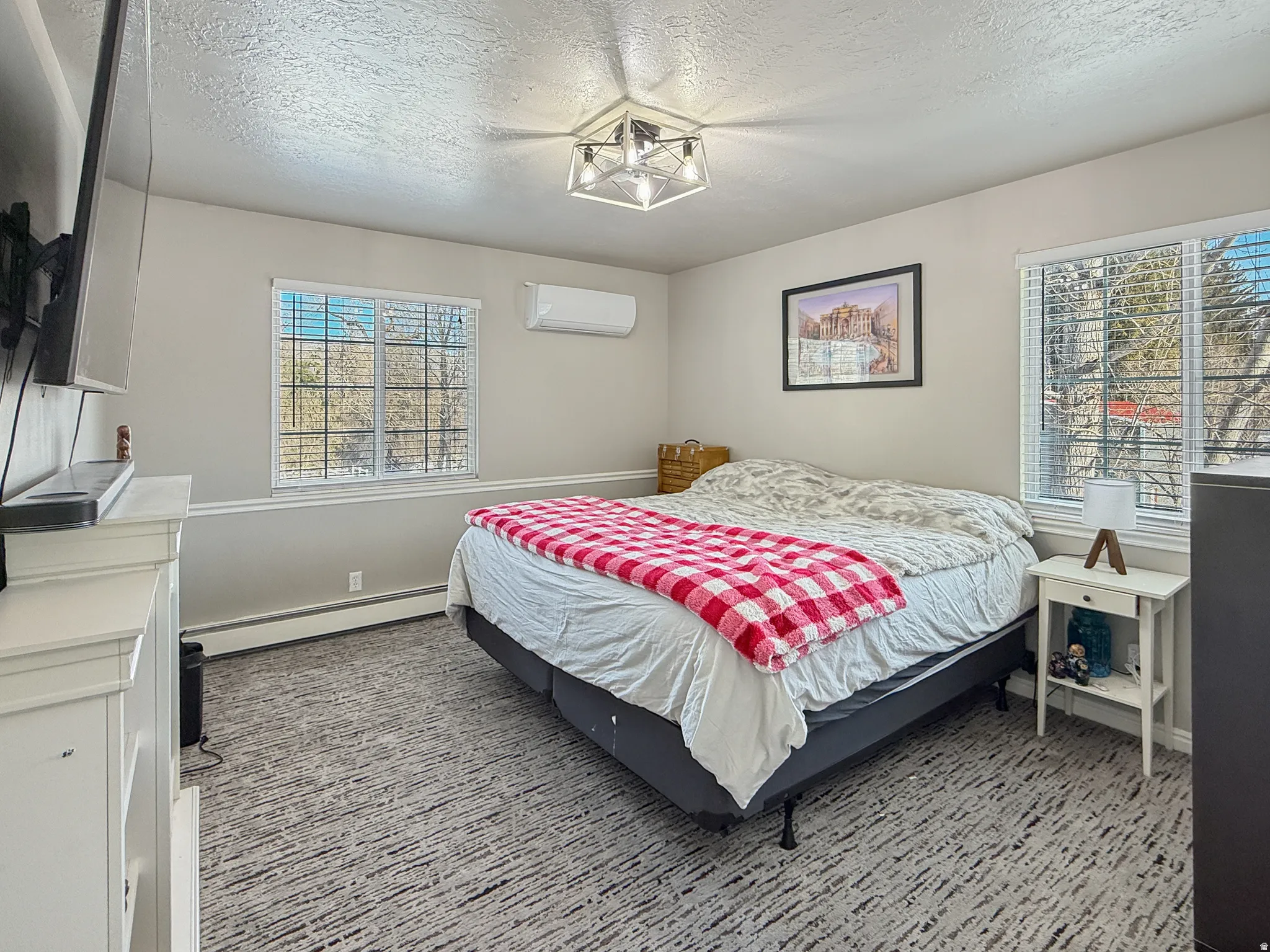 Bedroom with baseboard heating, a textured ceiling, and light carpet