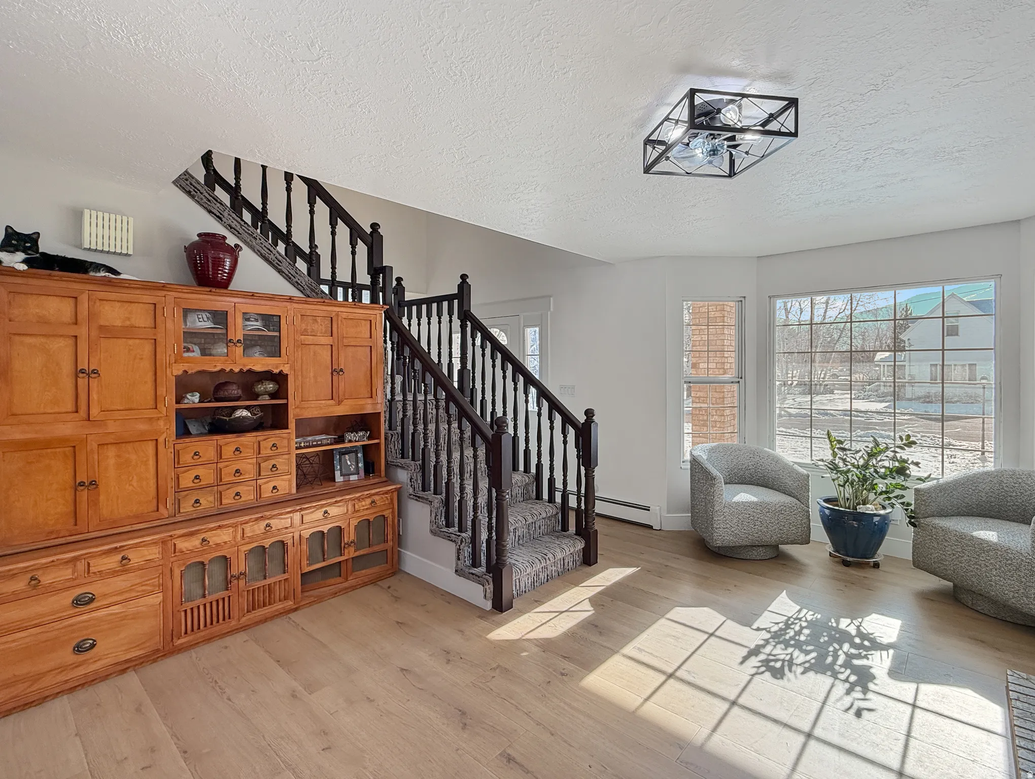 Stairway with wood finished floors, a textured ceiling, and a baseboard heating unit