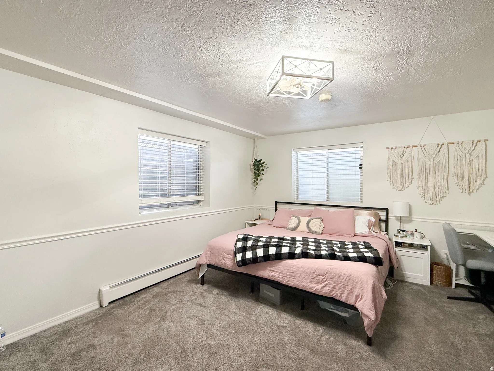 Bedroom with a baseboard radiator, carpet flooring, and a textured ceiling