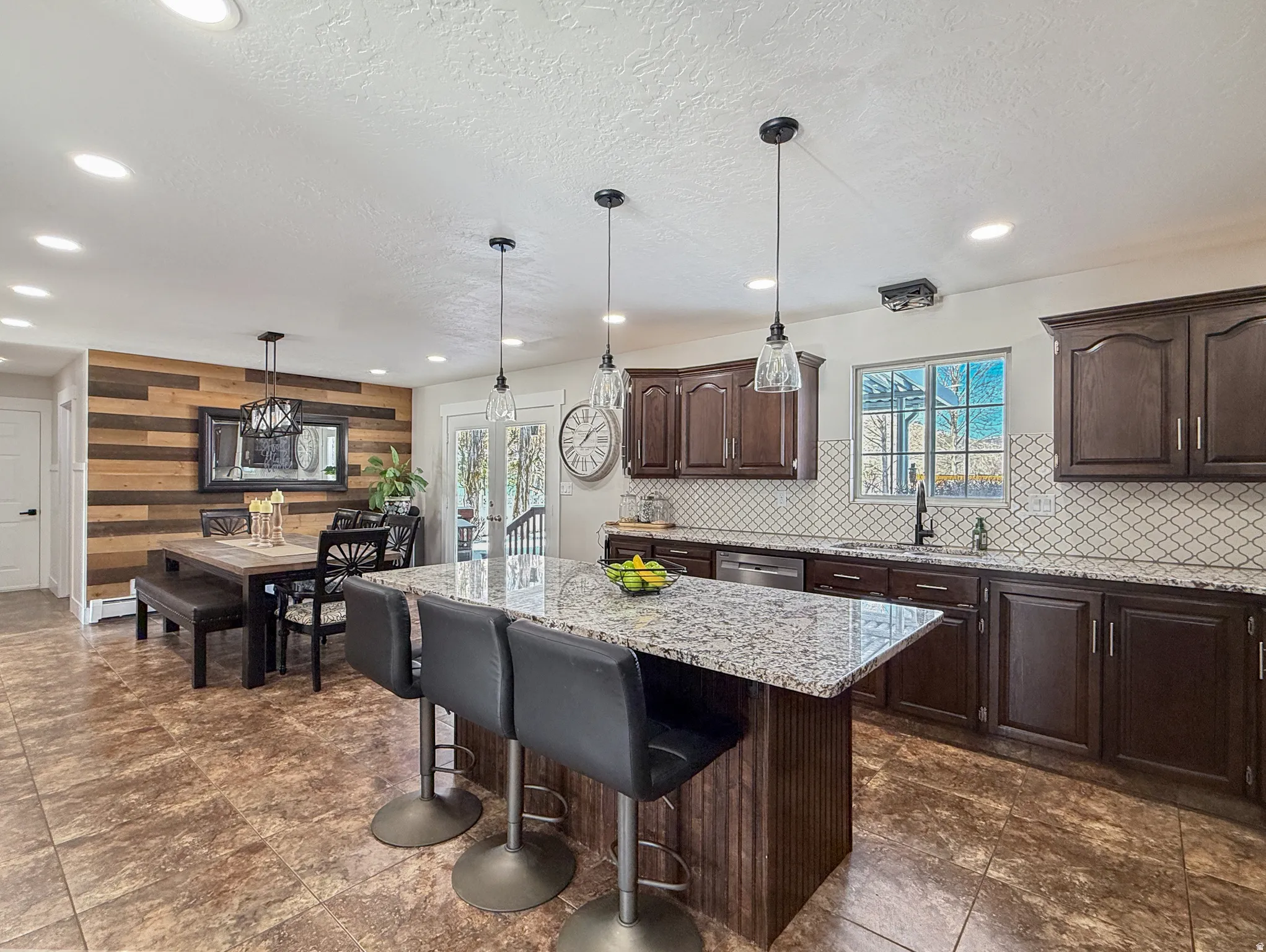 Kitchen with a breakfast bar area, a kitchen island, dark wood finish cabinetry, light stone countertops, and a textured ceiling