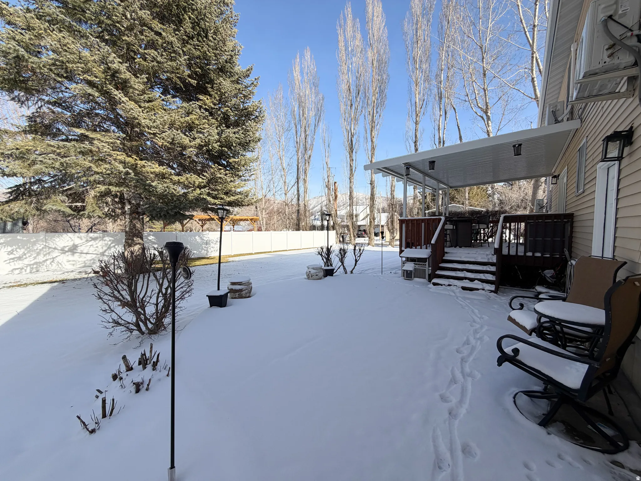 Yard layered in snow featuring a fenced backyard and a wooden deck