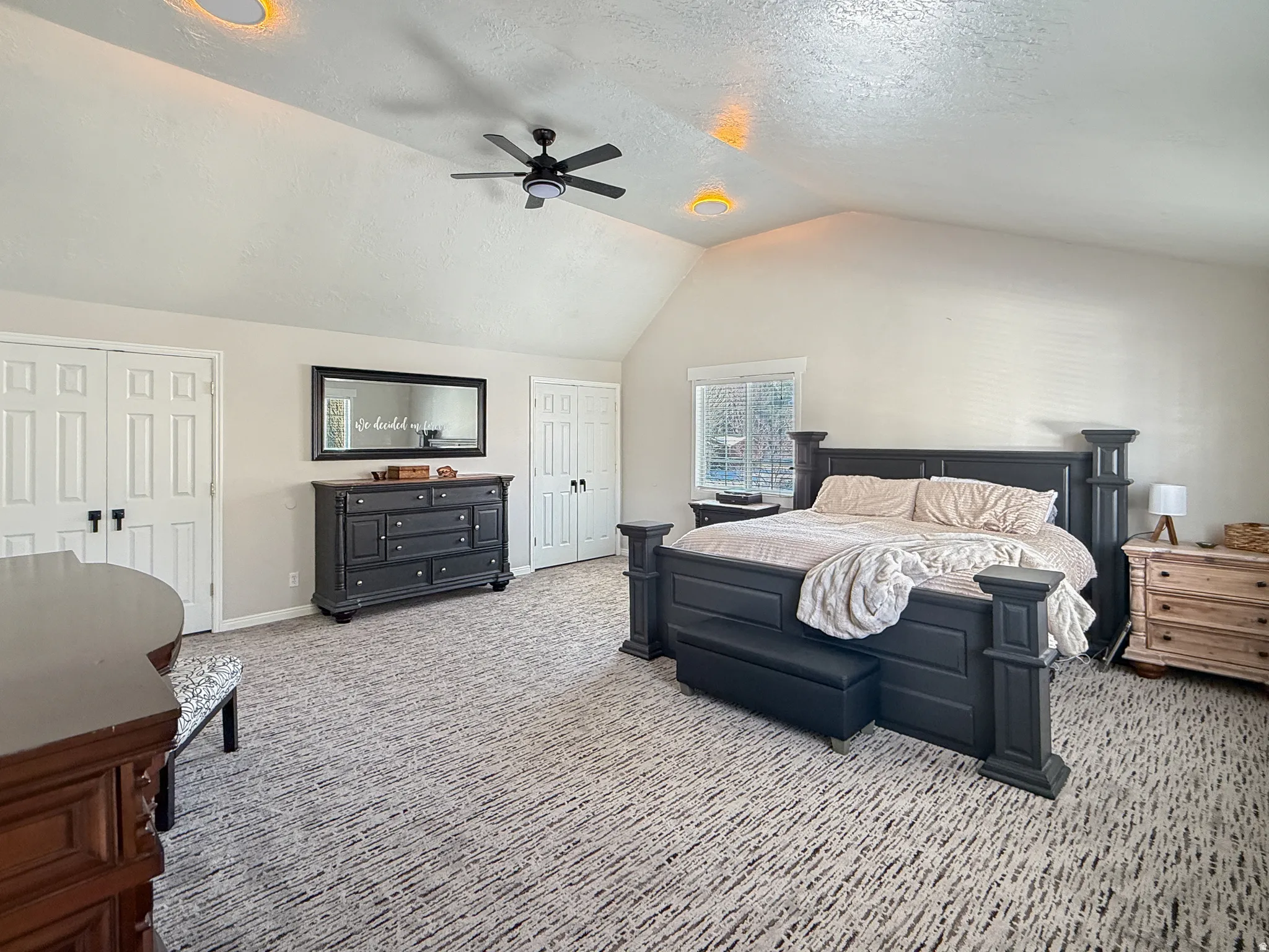 Bedroom with a textured ceiling, light colored carpet, ceiling fan, and multiple closets