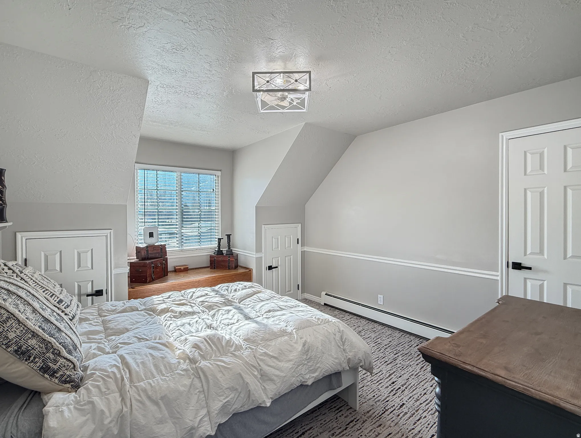Bedroom with a textured ceiling and a baseboard radiator