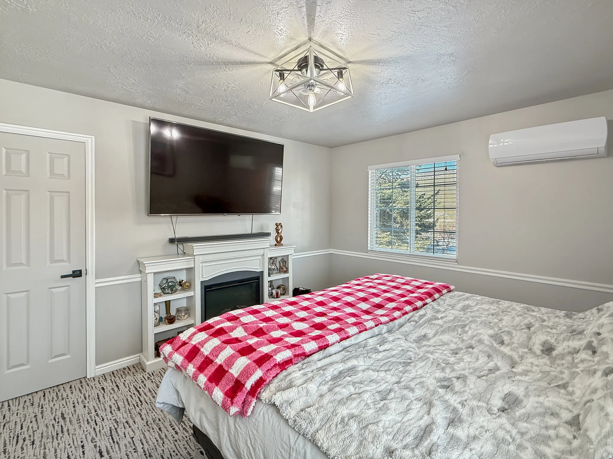 Bedroom featuring a textured ceiling, light carpet, and a fireplace