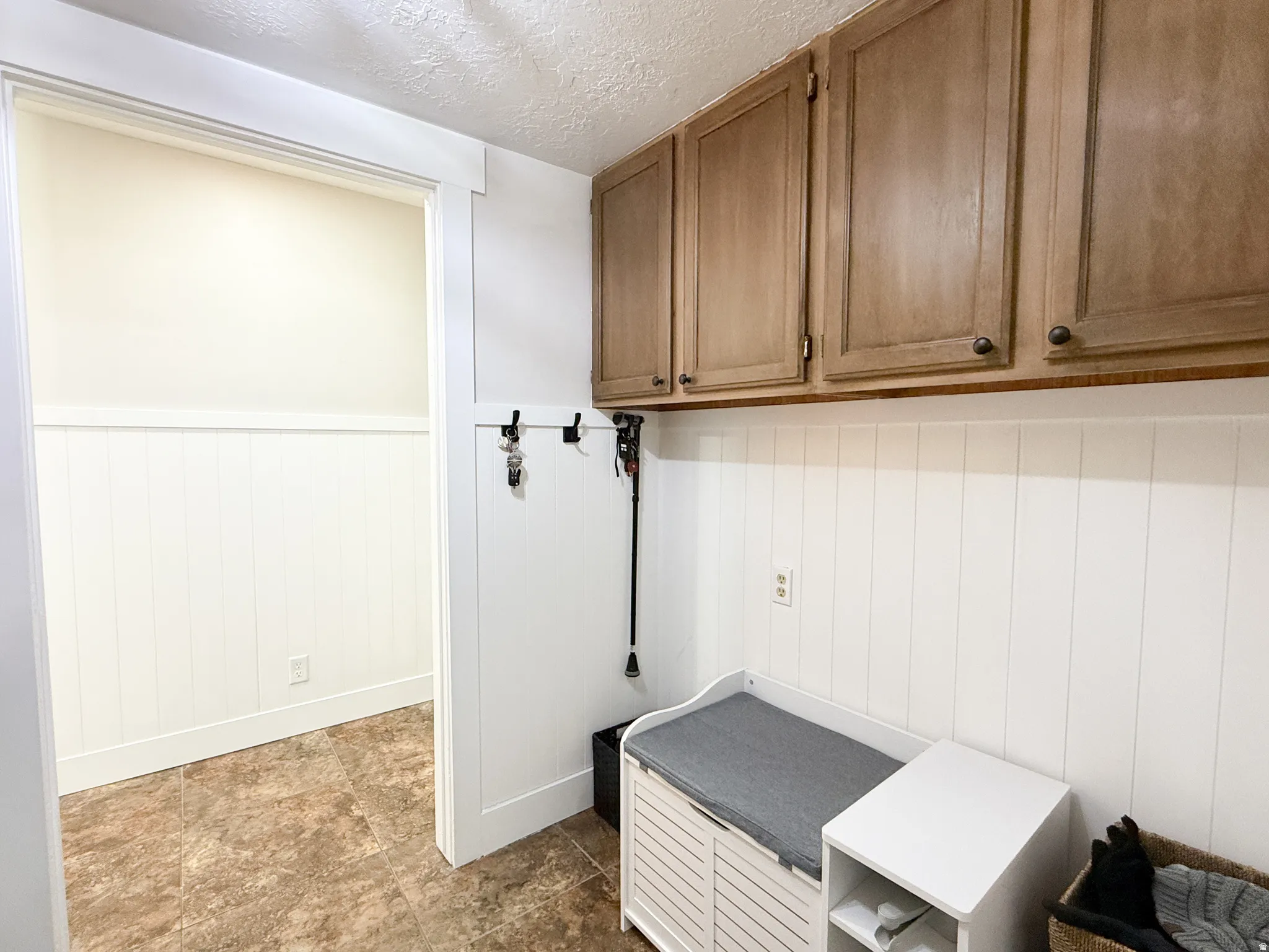 Mudroom with a textured ceiling and a wainscoted wall