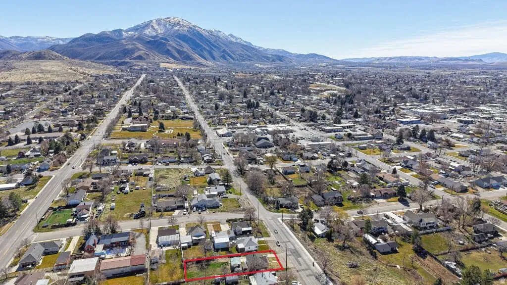 Aerial perspective of suburban area with a mountain backdrop and property parcel outlined