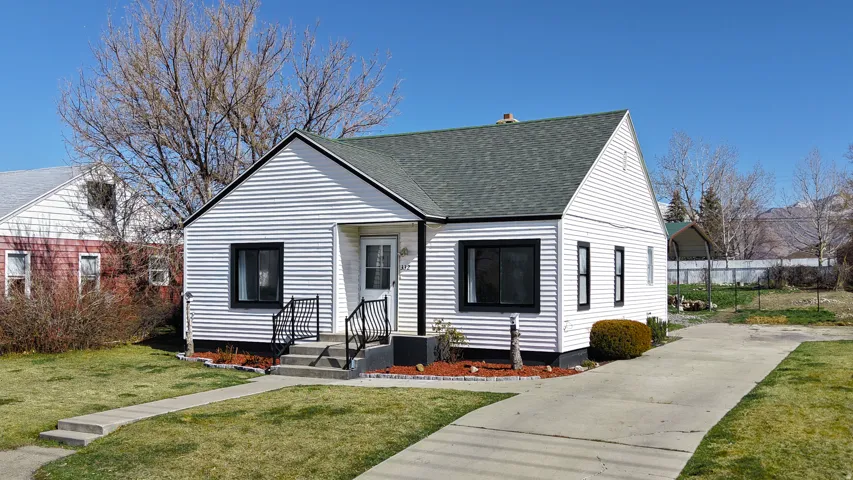 Bungalow-style house featuring a front lawn, a shingled roof, and concrete driveway