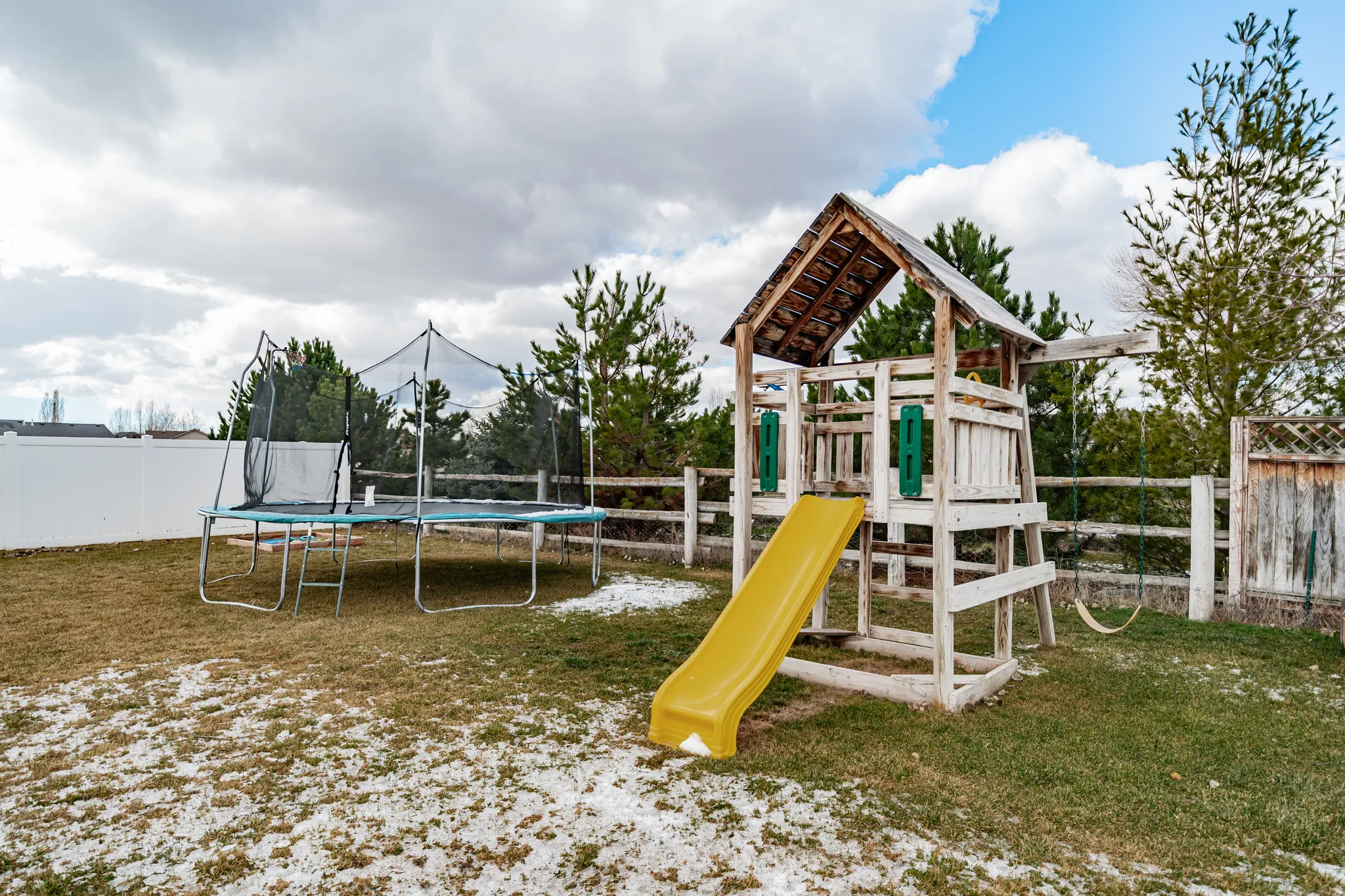 View of jungle gym with a fenced backyard and a trampoline