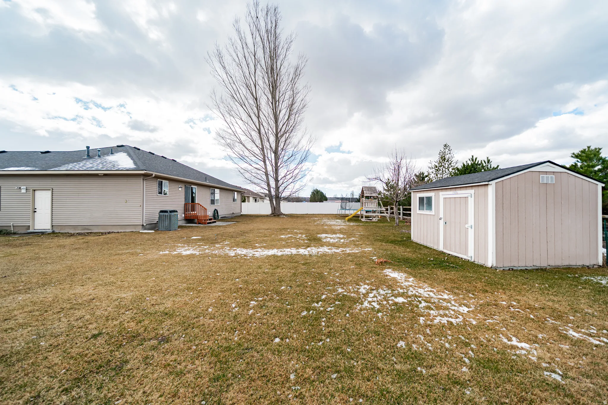View of yard featuring a trampoline and a storage unit