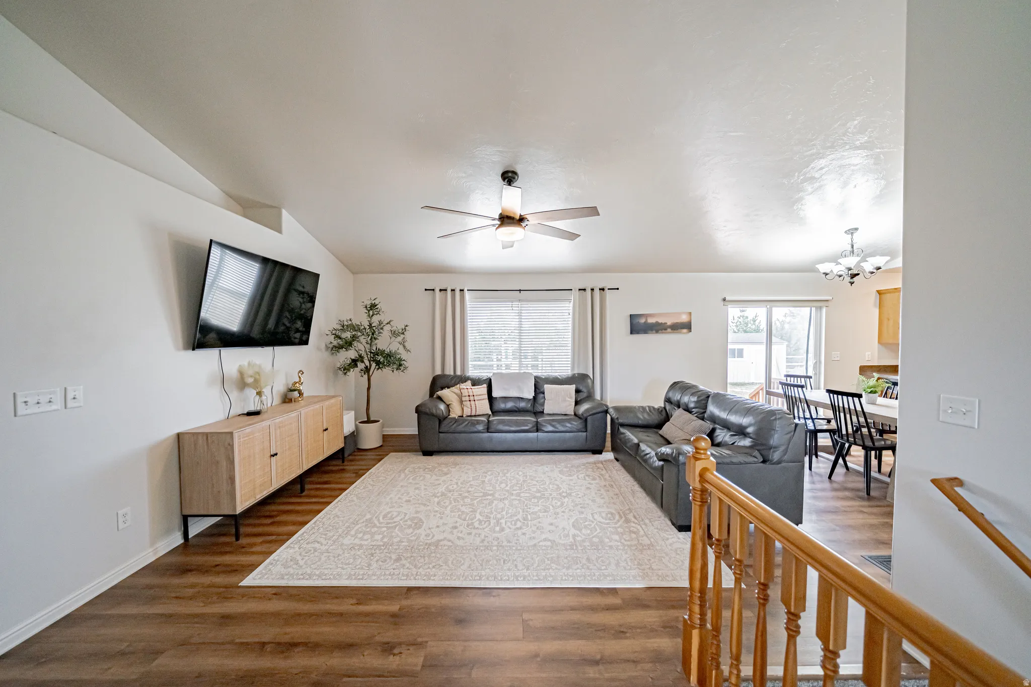 Living room with dark wood-type flooring, ceiling fan, a chandelier, and vaulted ceiling