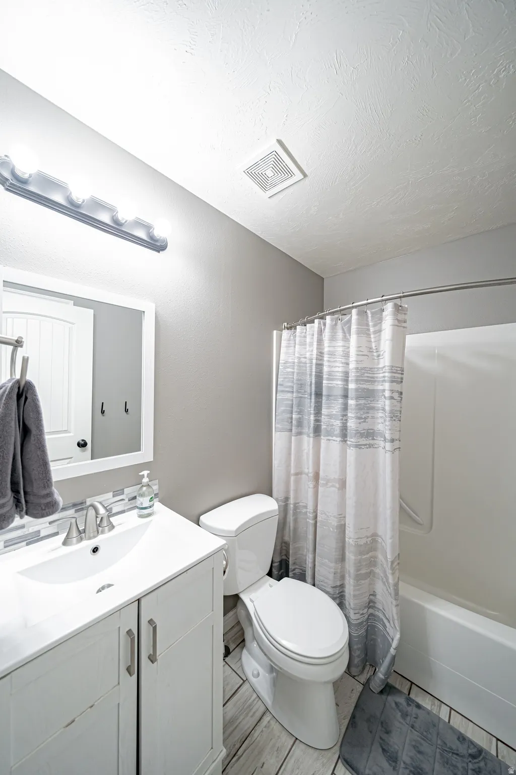 Bathroom featuring vanity, shower / bath combo with shower curtain, and a textured ceiling