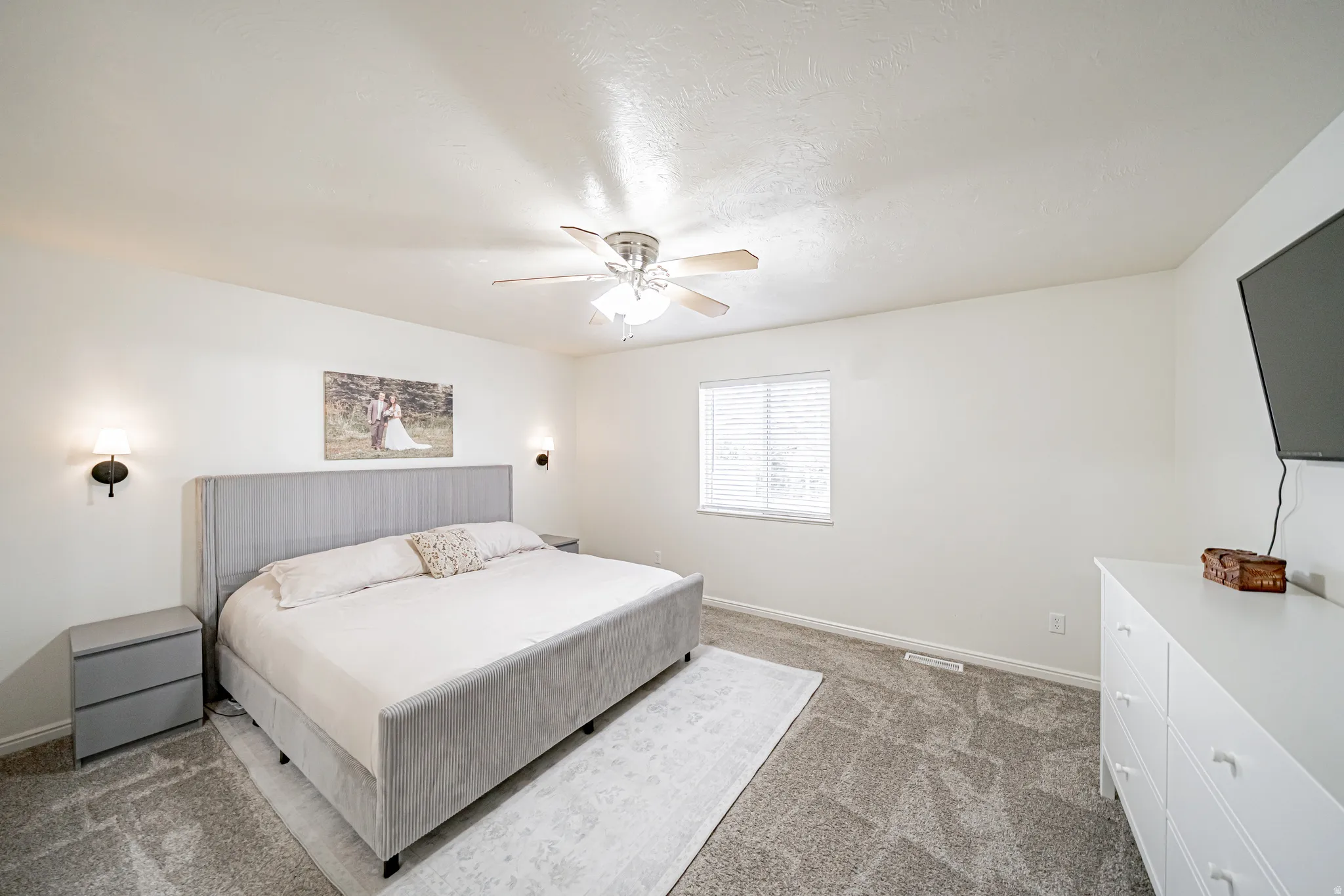 Carpeted bedroom with ceiling fan and a textured ceiling