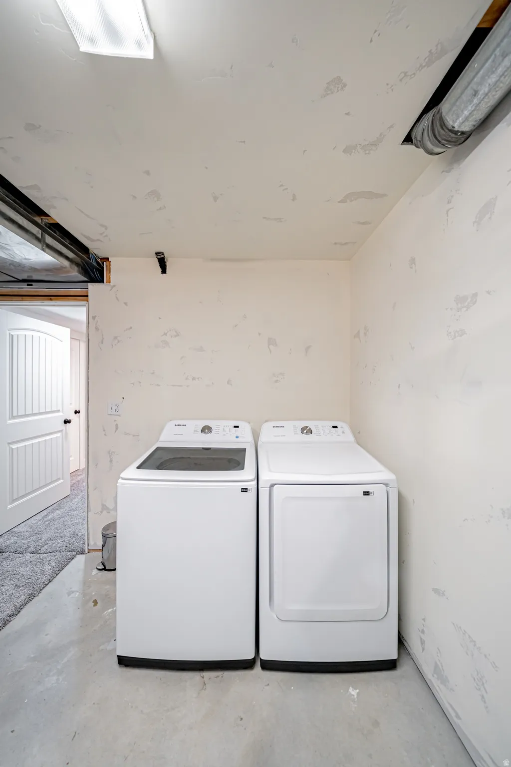 Laundry area featuring unfinished concrete flooring and washing machine and dryer