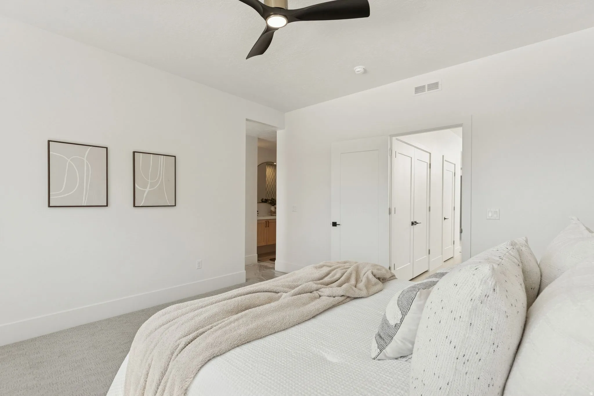 Carpeted bedroom featuring ceiling fan and ensuite bath