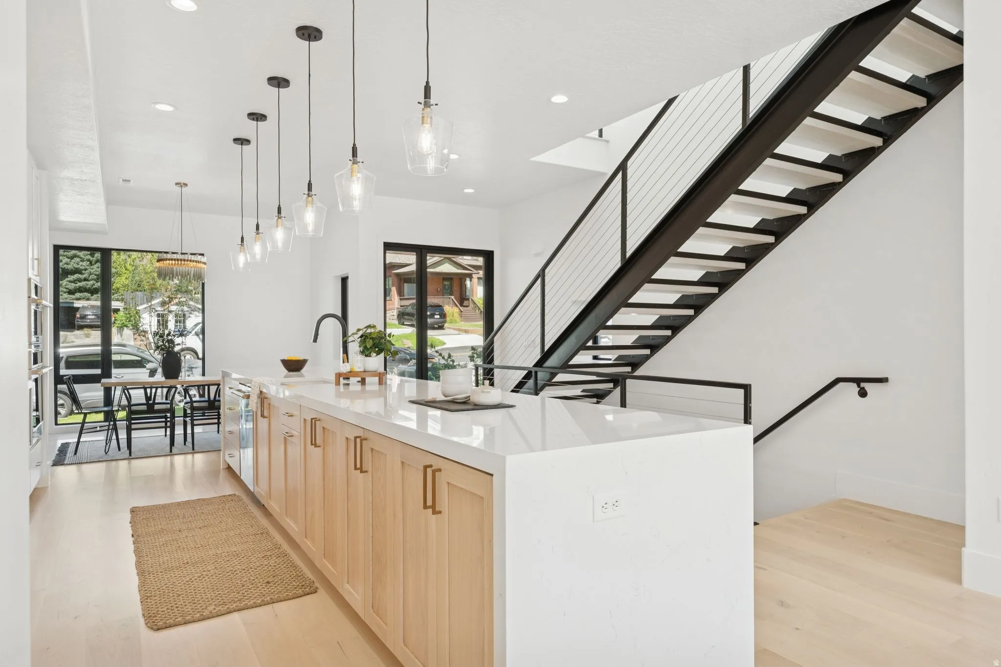 Kitchen with light wood finish cabinets, a spacious island, light wood finished floors, light stone counters, and pendant lighting