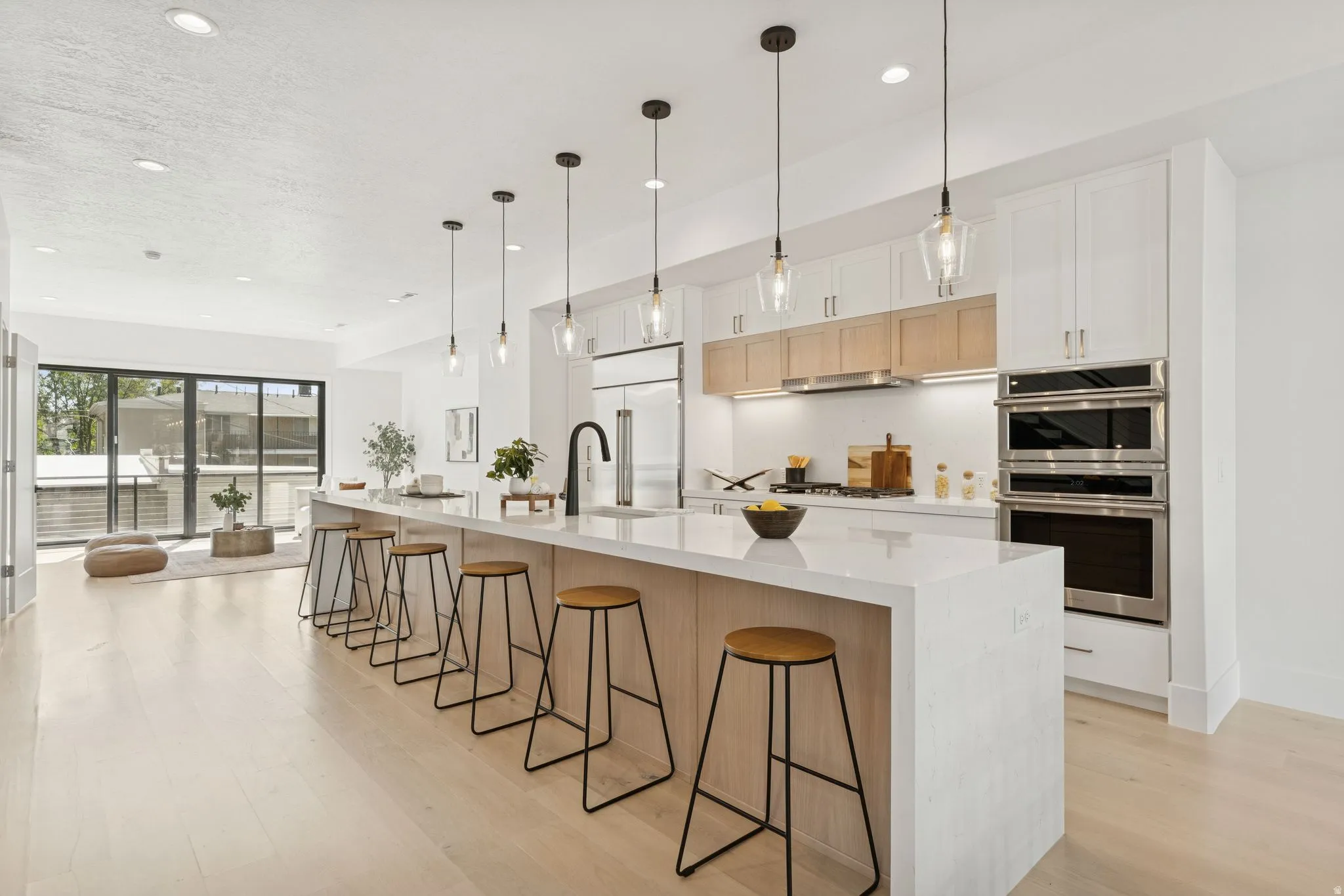 Kitchen featuring a kitchen bar, light wood-type flooring, light wood finish cabinets, stainless steel appliances, and a spacious island