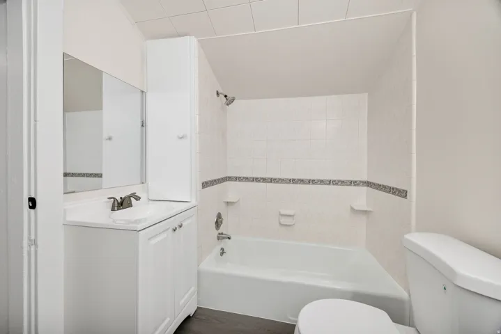 Bathroom with vanity, bathing tub / shower combination, and dark wood-style flooring