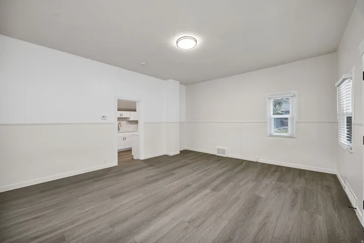 Empty room featuring dark wood-type flooring and baseboards