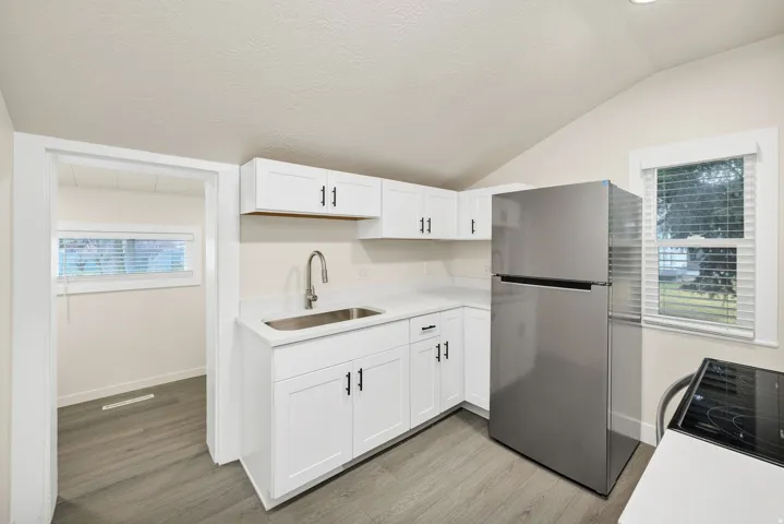 Kitchen with freestanding refrigerator, plenty of natural light, white cabinets, and light wood-type flooring