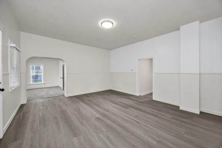 Unfurnished room featuring wood finished floors and arched walkways
