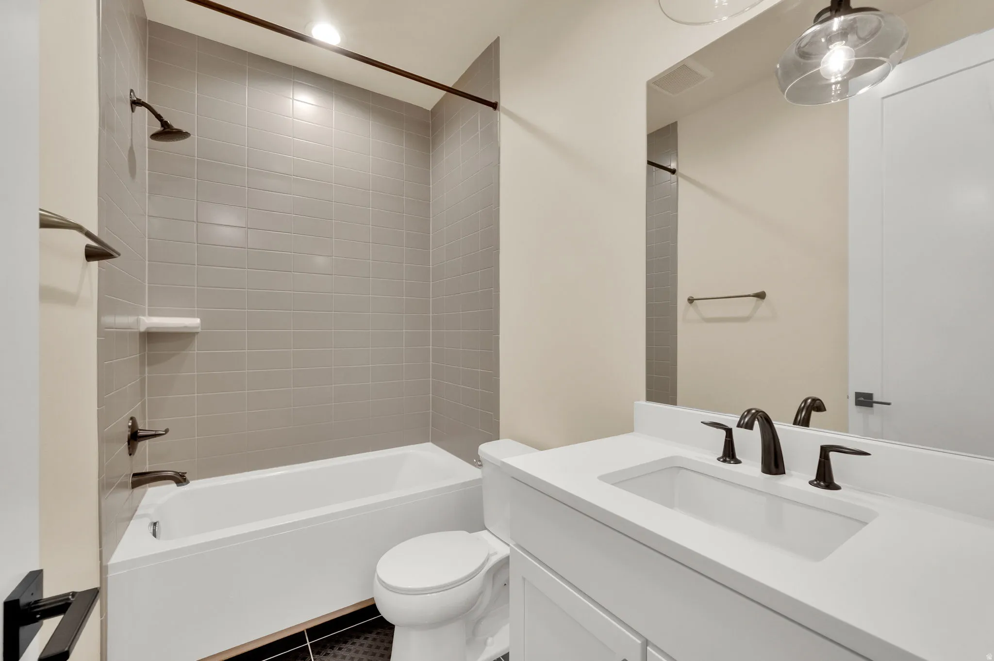 Bathroom with vanity,  shower combination, dark tile patterned floors, and recessed lighting