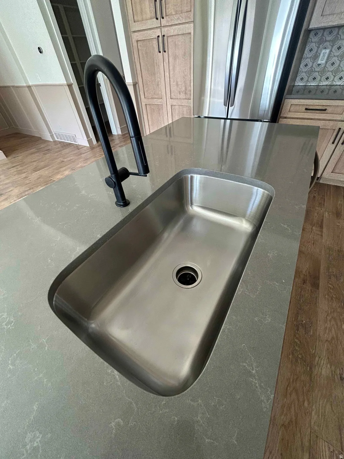 Kitchen view of wood finished floors, freestanding refrigerator, and dark stone countertops