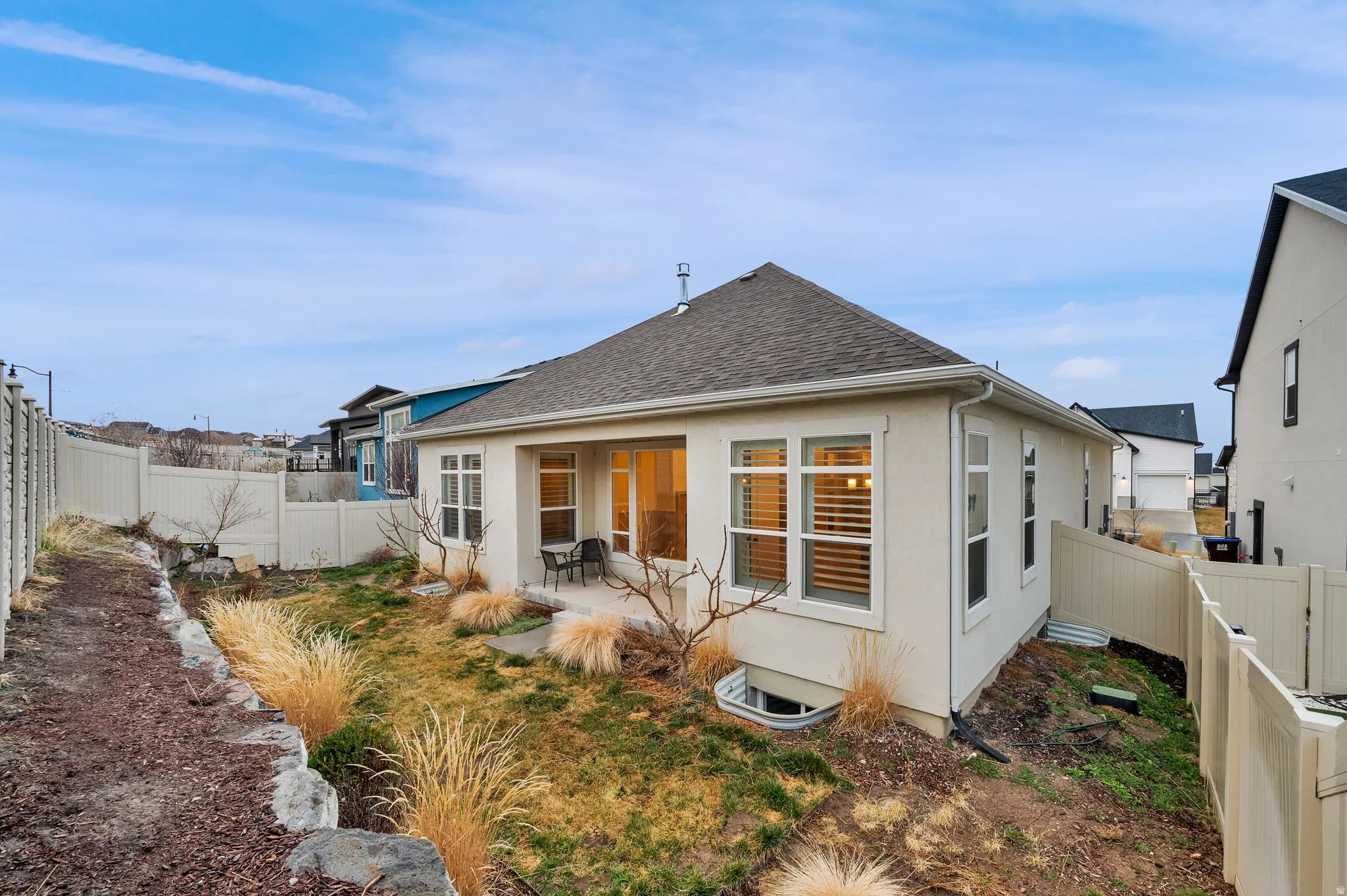 Back of house with a patio area, a fenced backyard, stucco siding, and roof with shingles