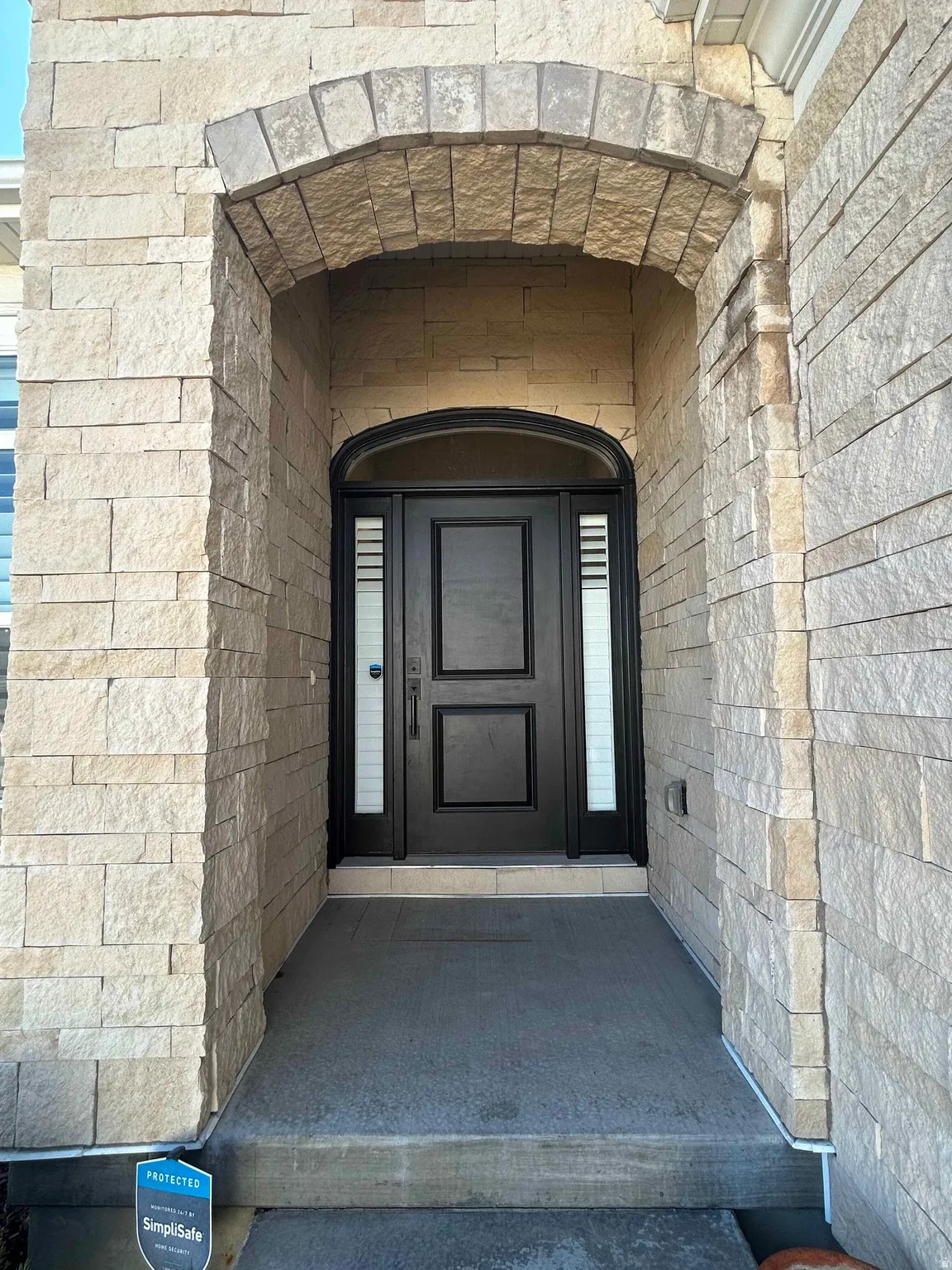 View of exterior entry with stone siding and brick siding
