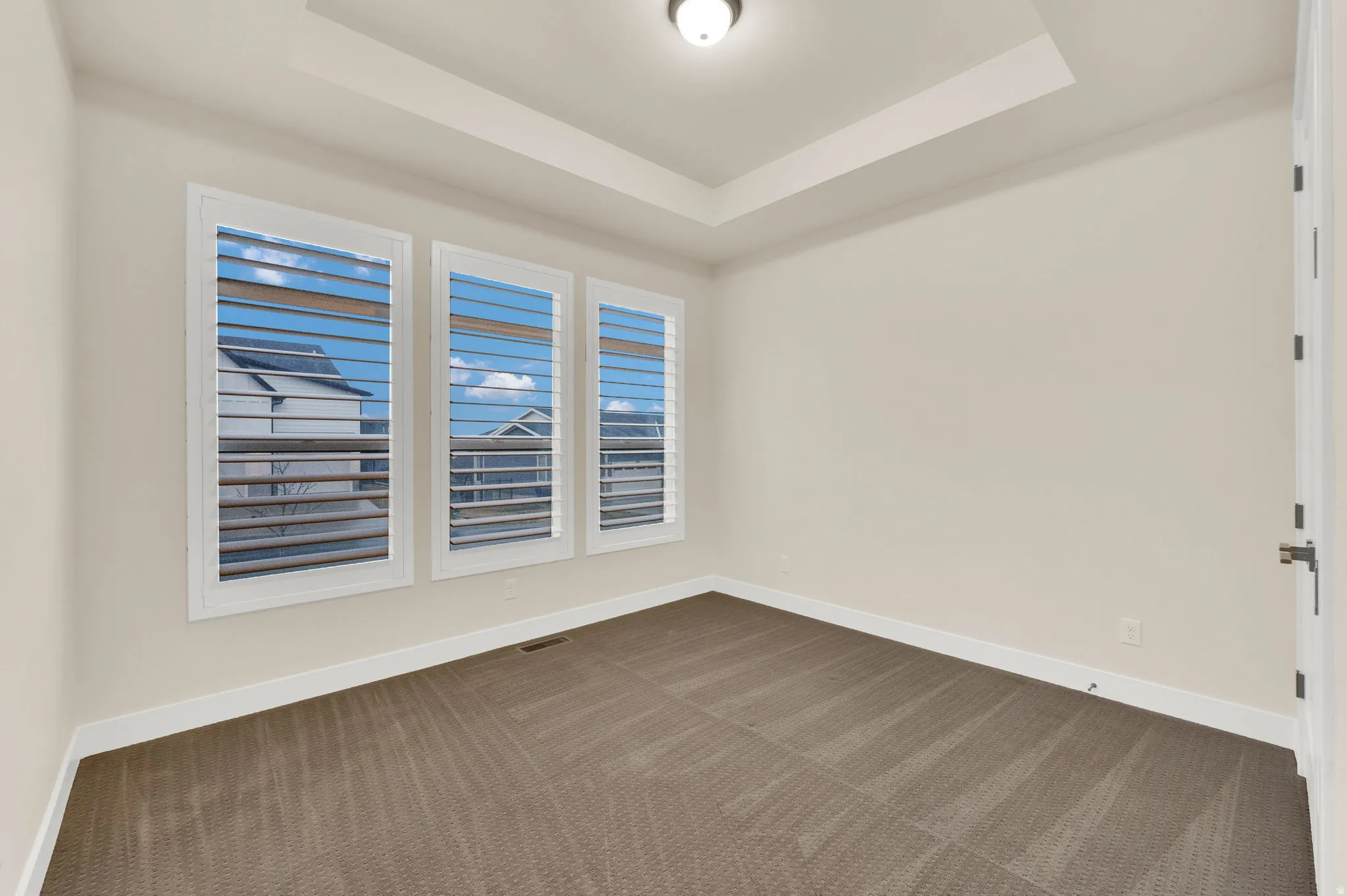 Empty room with dark colored carpet and a raised ceiling